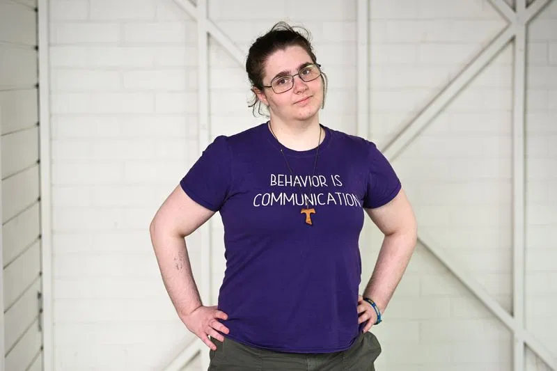 A white woman with brown hair, standing up with her hands on her hips looking unhappy.